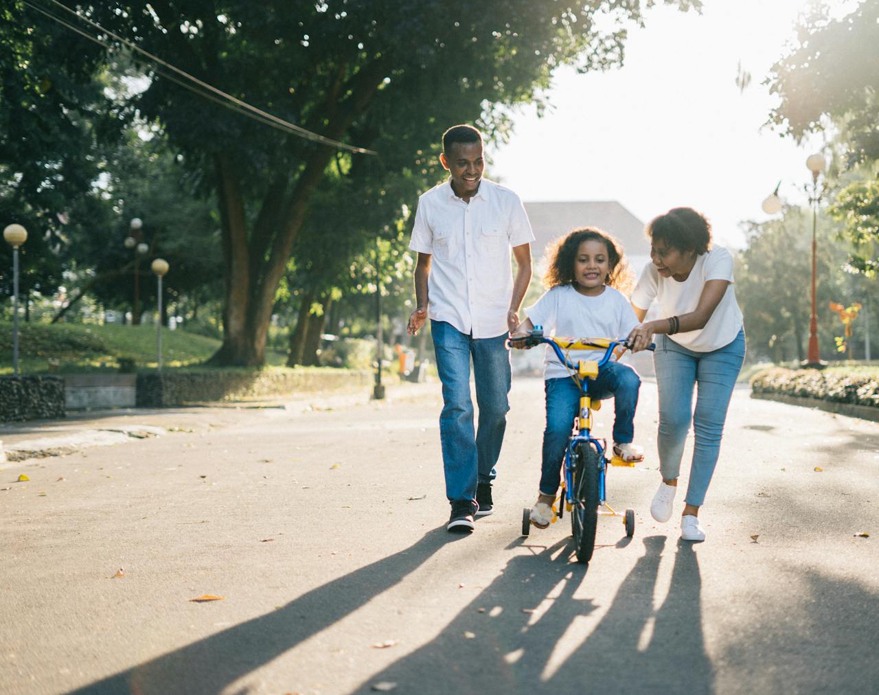 services-01 Happy family teaching their child to cycle on a sunny day outdoors.
