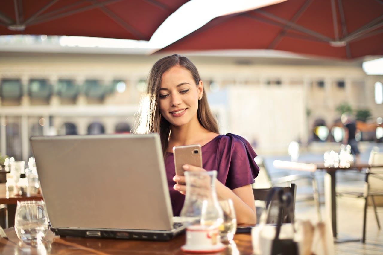 about-02 Woman enjoying remote work at a café, using a laptop and smartphone.